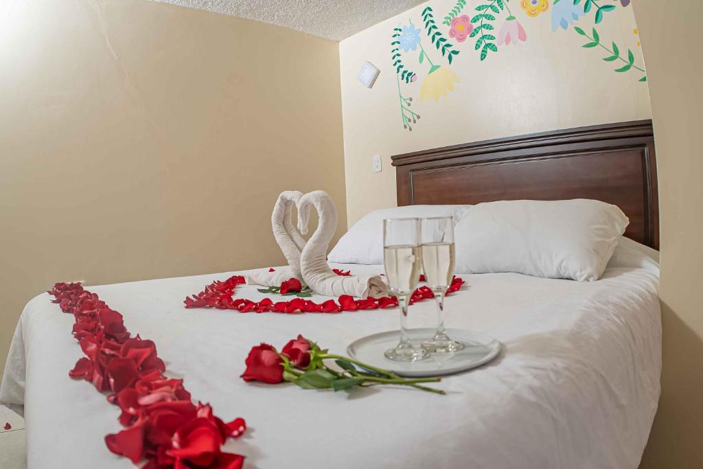 Una cama con rosas y dos copas de champán. en Hotel Tungurahua, en Baños