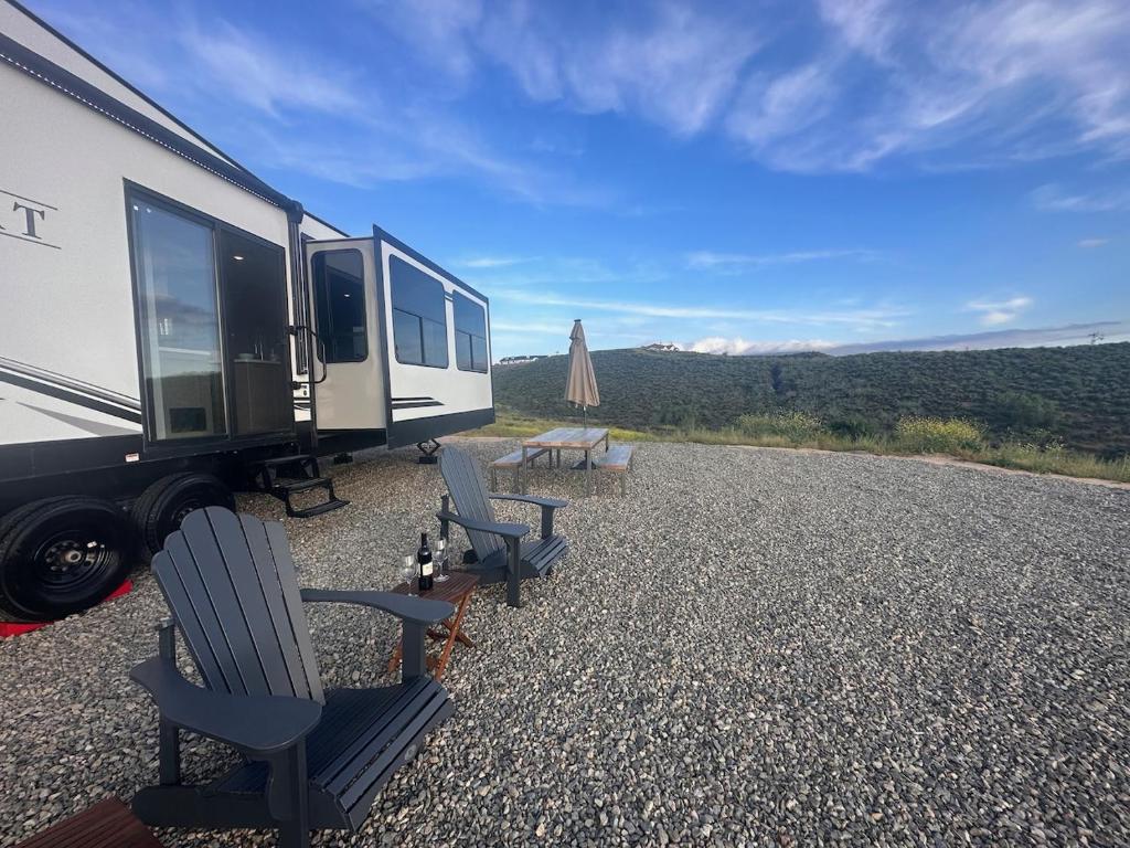an rv with two chairs and a table and a picnic table at Temecula Hilltop View Glamping Next To Wineries in Temecula