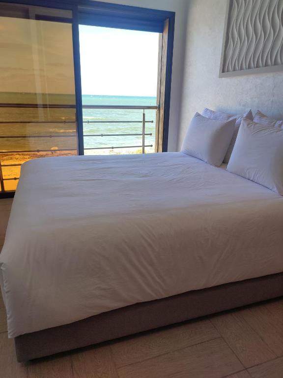 - un grand lit blanc avec vue sur l'océan dans l'établissement clapotis, à El Jadida