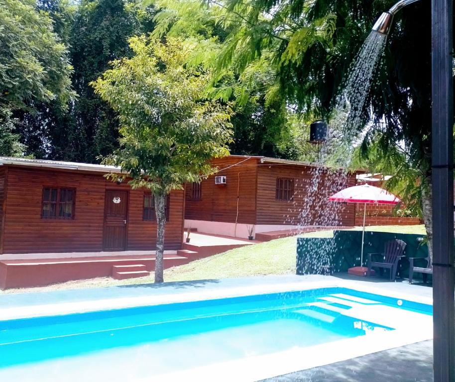 a swimming pool with a fountain in front of a house at Cabañas cerella in Puerto Iguazú