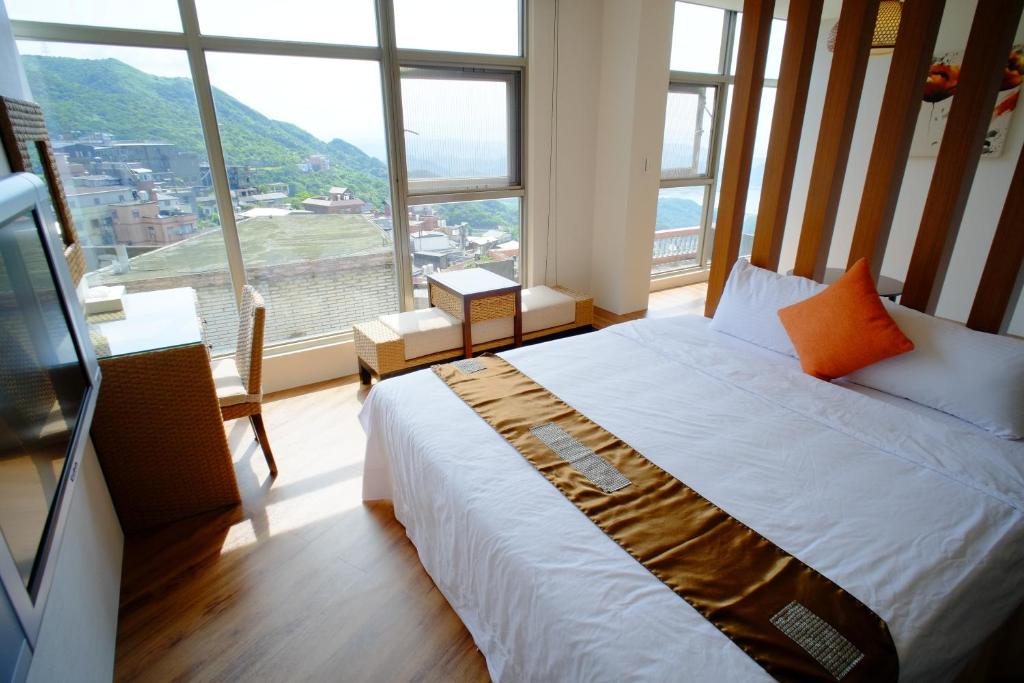 a bedroom with a bed and a large window at Chiu Chunt Dint B&amp;B in Jiufen