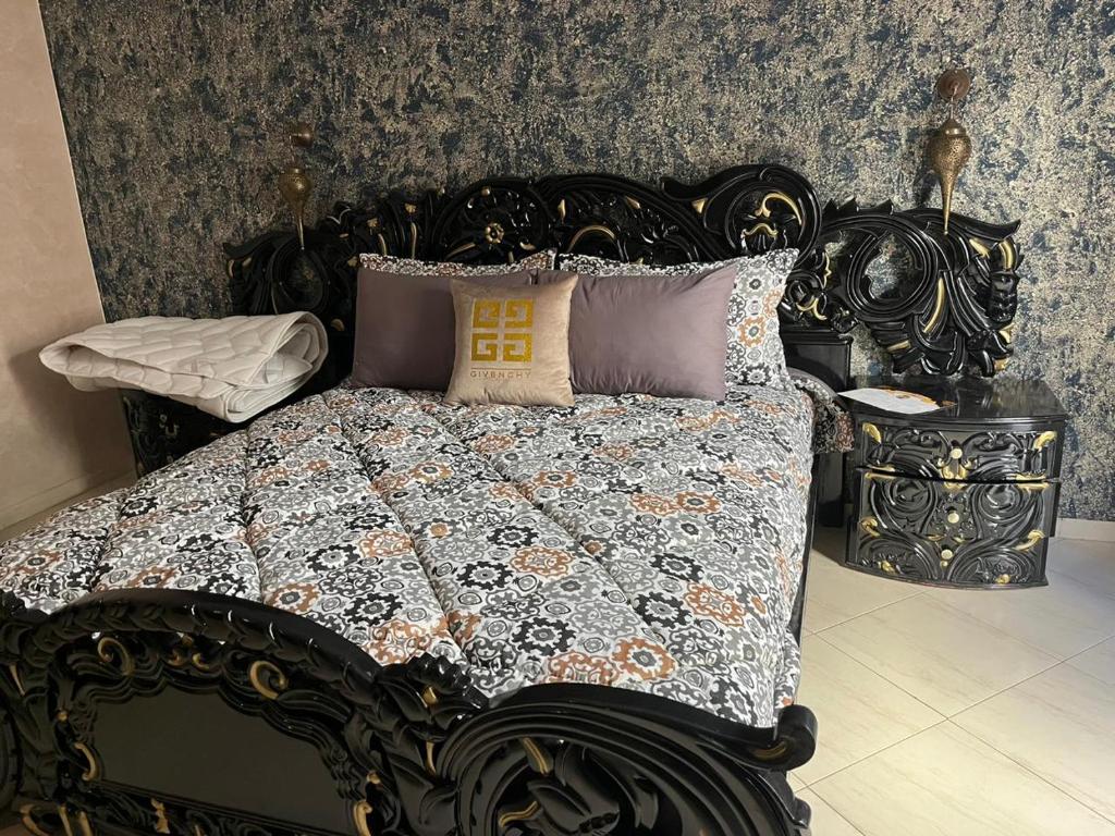 un letto nero con trapunta e cuscini sopra di Appartement centre-ville a Fes