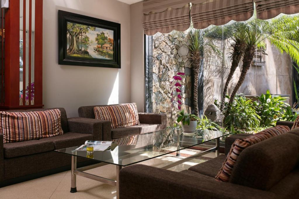 ein Wohnzimmer mit Sofas und einem Glastisch in der Unterkunft Sen Hotel - Managed by Sen Hotel Group in Hanoi