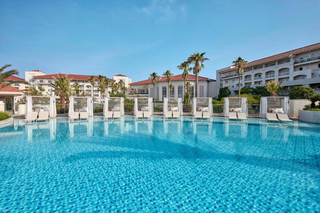 a large swimming pool with chairs and a building at The Shilla Jeju in Seogwipo