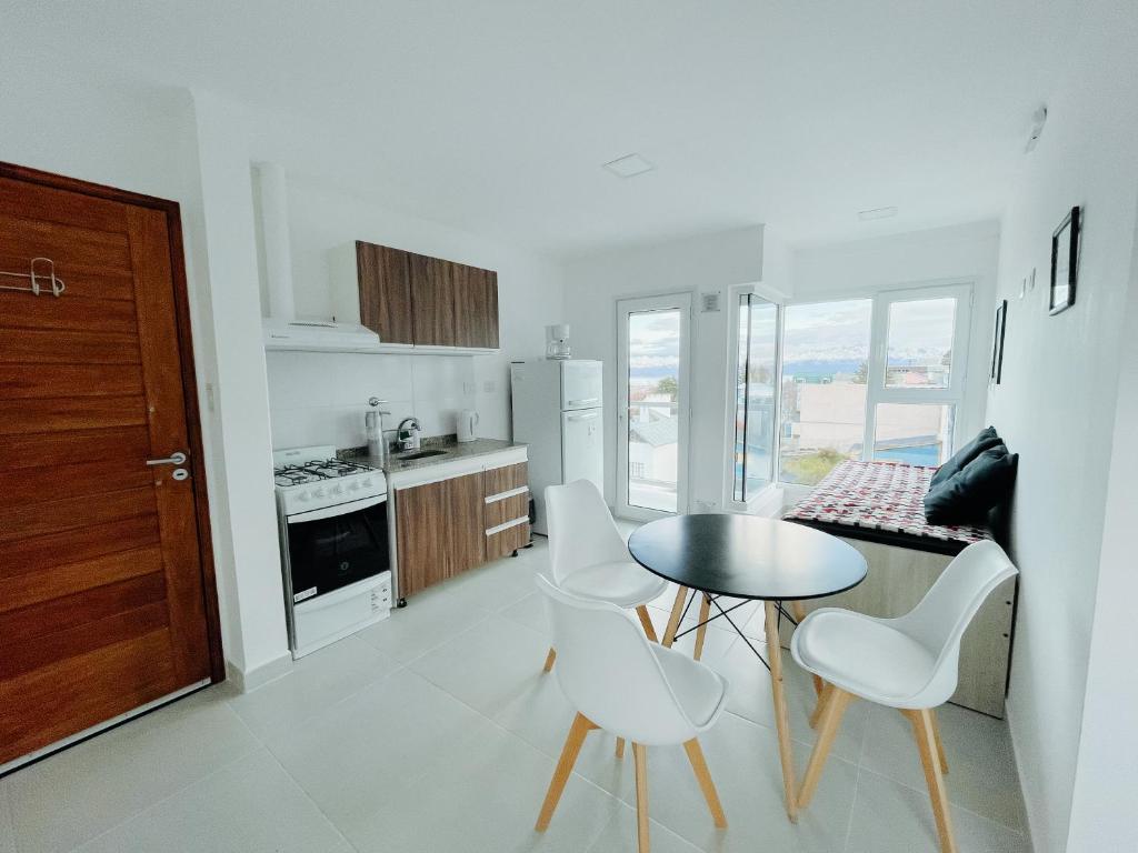 Una cocina con una mesa y algunas sillas blancas y una mesa. en Altos de Cervantes, en Ushuaia