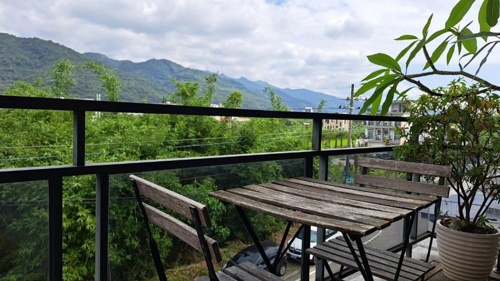 a wooden table and bench on a balcony with mountains at Jiaoxi Song Tian B&B in Jiaoxi