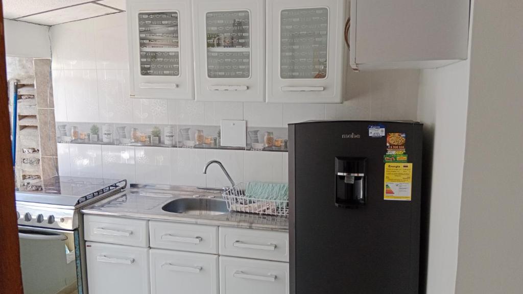 eine Küche mit einem schwarzen Kühlschrank und einer Spüle in der Unterkunft Alojamiento cómodo en una ubicación maravillosa! in Cartagena de Indias