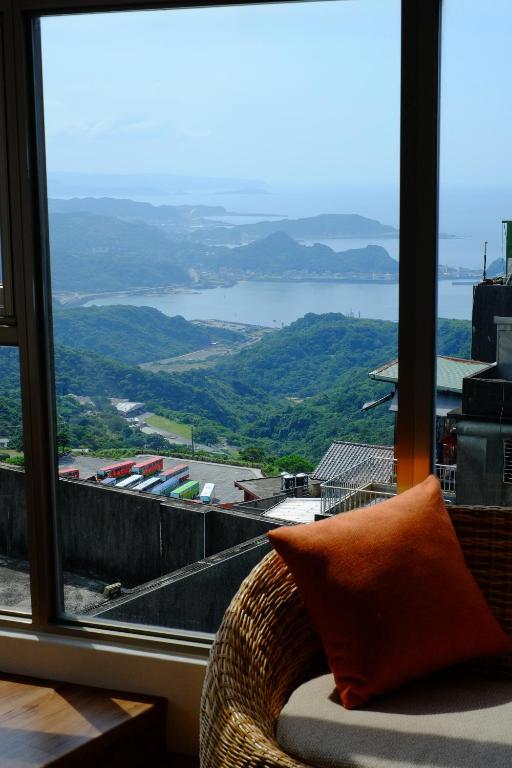 a chair with an orange pillow sitting in front of a window at Chiu Chunt Dint B&amp;B in Jiufen