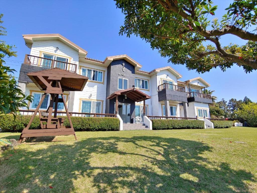 a large house with a playground in front of it at Gyulhouse Pension in Seogwipo