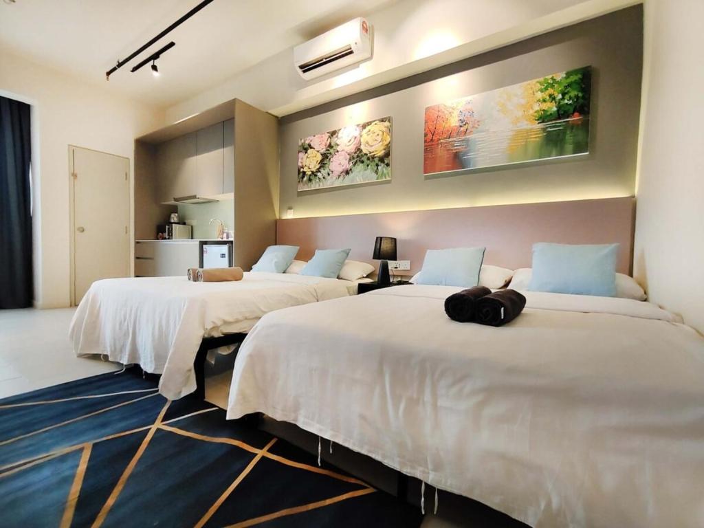 Zimmer mit 3 Betten und weißer Bettwäsche in der Unterkunft Tamarind Suites Cyberjaya in Cyberjaya