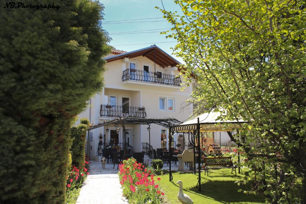 ein weißes Gebäude mit einem Balkon und einem Vogel im Hof in der Unterkunft Pension Lale in Peštani