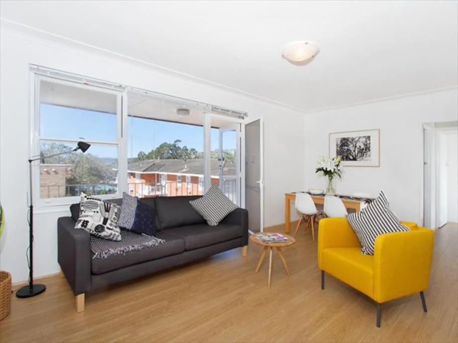 een woonkamer met een zwarte bank en een gele stoel bij BOT01 - Balmoral Light and Airy Beach Apartment in Sydney