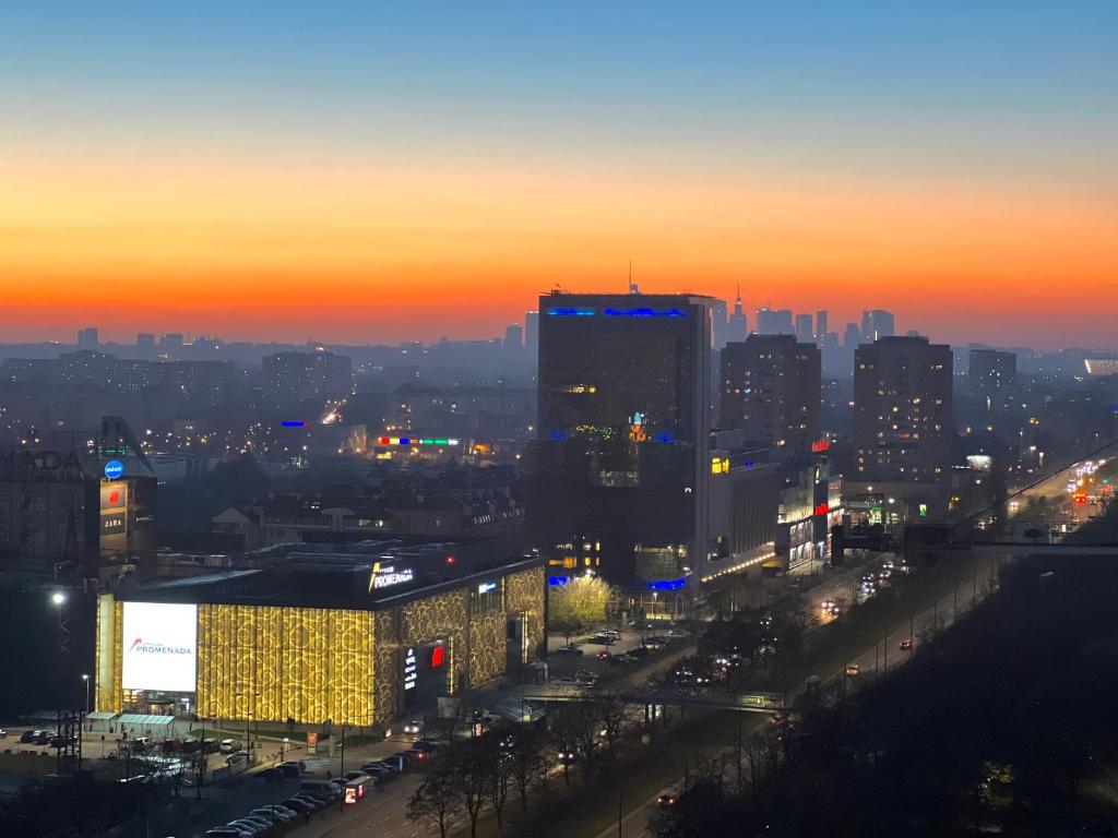 een skyline van de stad bij zonsondergang met gebouwen en verkeer bij Apartament SKYSCRAPPER z widokiem na panoramę Warszawy in Warschau