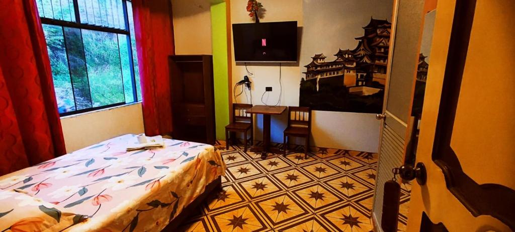 a bedroom with a bed and a table and a window at HOSPEDAJE EL CANTARO in Tingo María