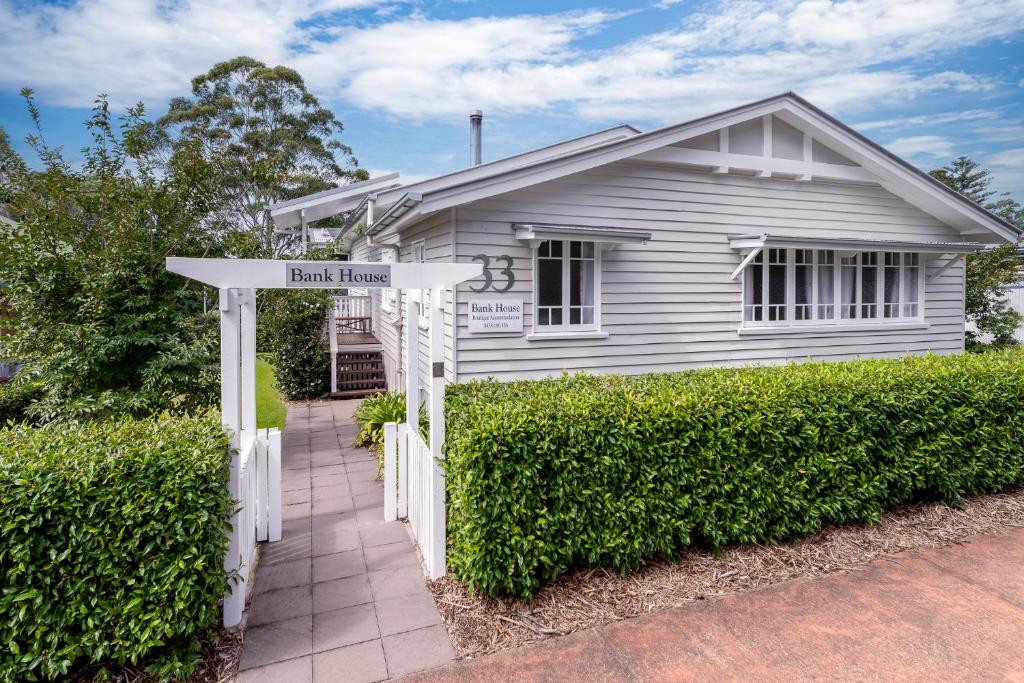 une maison blanche avec un panneau de rue devant elle dans l'établissement Bank House Tamborine Mountain, à Mount Tamborine