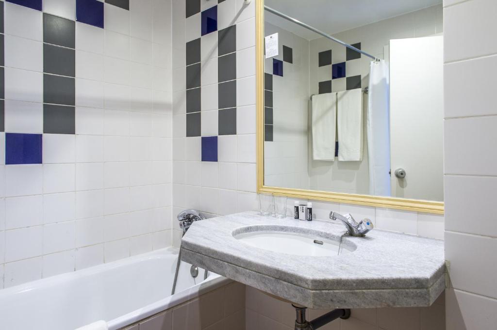 a bathroom with a sink and a mirror and a tub at Hotel Londres Estoril / Cascais in Estoril