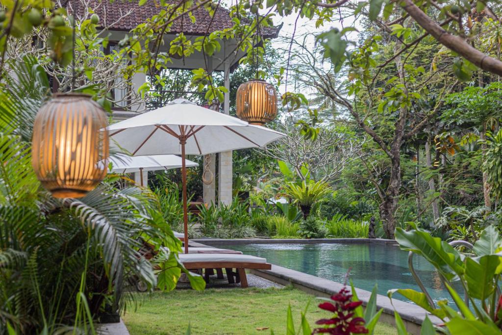 um resort com uma piscina, um guarda-sol e uma mesa em Suara Air Luxury Villa Ubud em Ubud