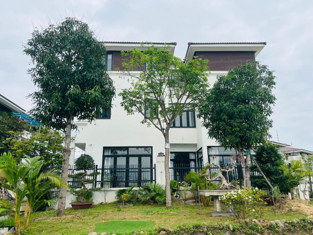 ein weißes Haus mit Bäumen davor in der Unterkunft Trippy villa: FLC Hạ Long in Hạ Long