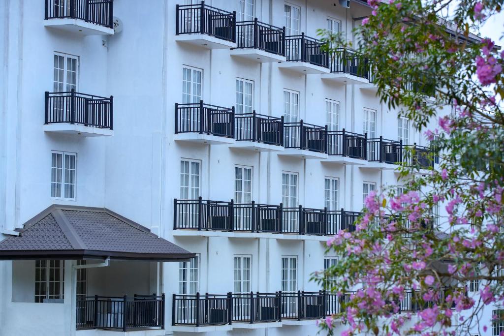 - un bâtiment blanc avec des balcons noirs et des fleurs roses dans l'établissement BPR - Asgiriya ,Kandy, à Kandy