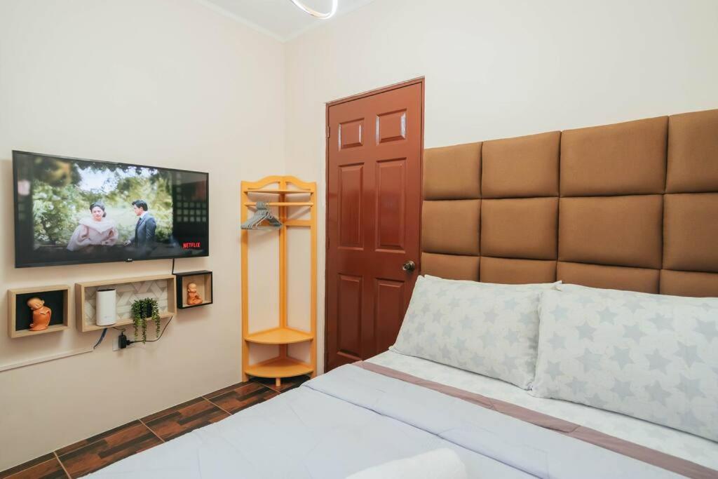 a bedroom with a bed and a flat screen tv at Cozy BNB - Unit G in Batangas City