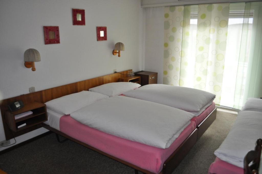 a bedroom with two beds and a window at Hotel de l'Union in Orsières