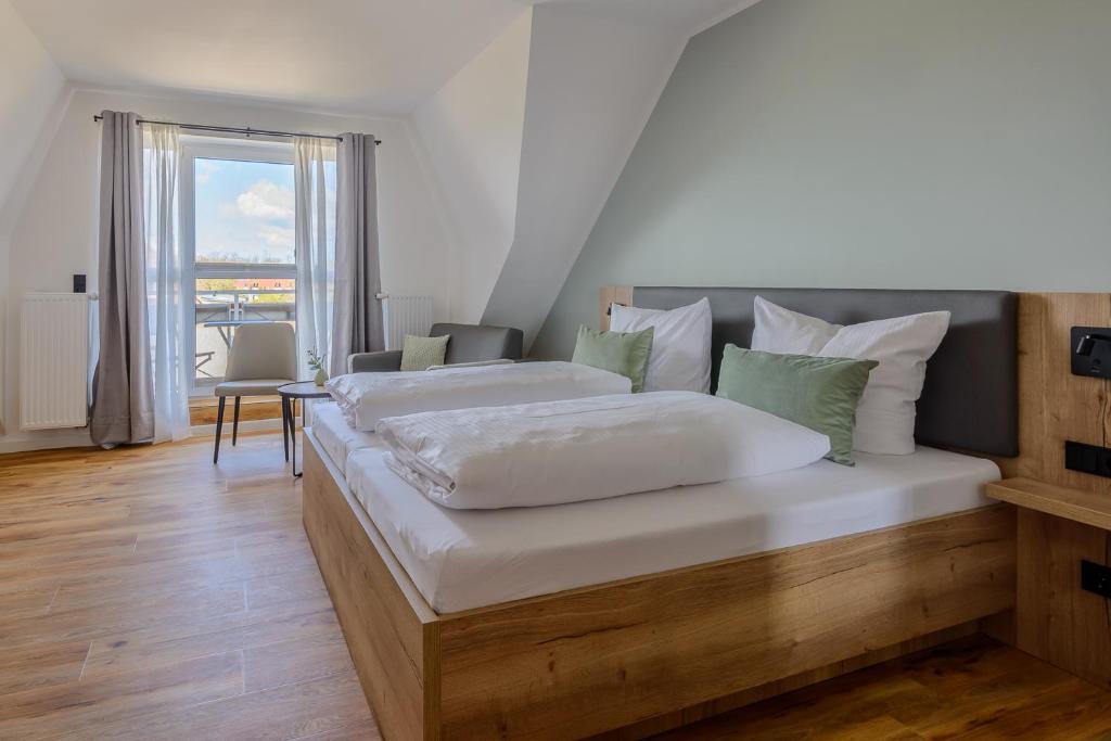 Cette chambre comprend un grand lit et une grande fenêtre. dans l'établissement Landhaus Nienhagen, à Nienhagen