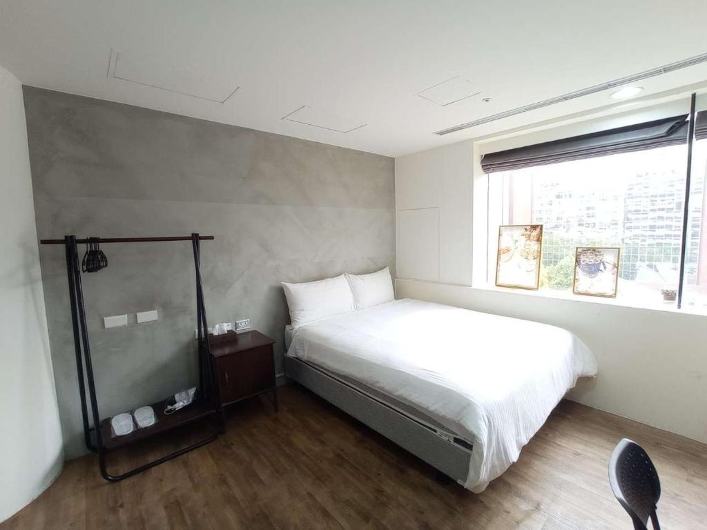 1 dormitorio con cama blanca y ventana en Happiness meworld, en Taipéi