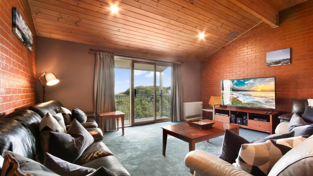 a living room with leather furniture and a large window at Lindsay Lachen in Mount Hotham