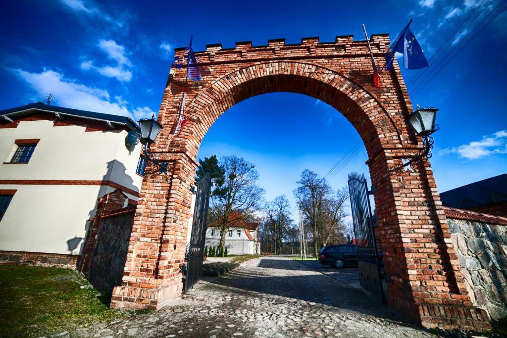 an archway in a brick wall next to a building at Dwór Kolesin in Nowe Kramsko