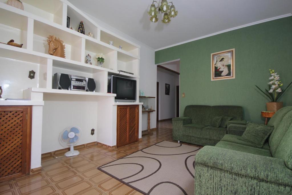 Sala de estar con 2 sofás verdes y TV en Casa Temporada GRATÃO 06 min dos parques Thermas, en Olímpia