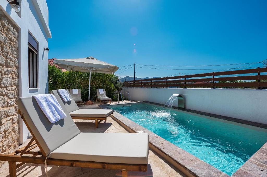 - une piscine avec 2 chaises et un parasol dans l'établissement Villa Estrella, à Égine