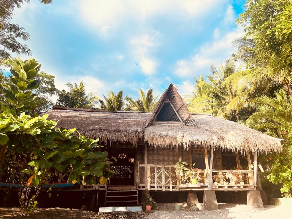 Hitokalak的住宿－The Sleepy Lagoon Beach House，海滩上带草屋顶的小屋