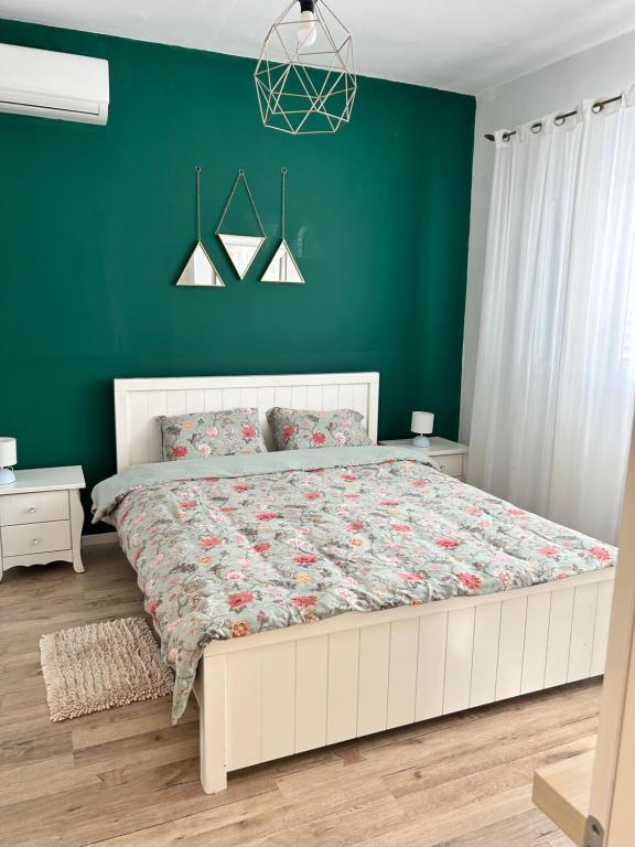sypialnia z dużym łóżkiem i zieloną ścianą w obiekcie 2 Bedrooms Apartment " Marcheliz " in Bat-yam w mieście Bat Jam
