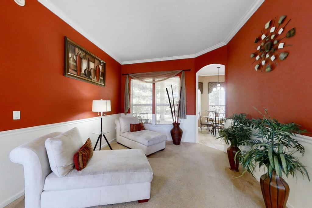 un soggiorno con 2 divani bianchi e pareti arancioni di The Yellow Hibiscus a Jacksonville