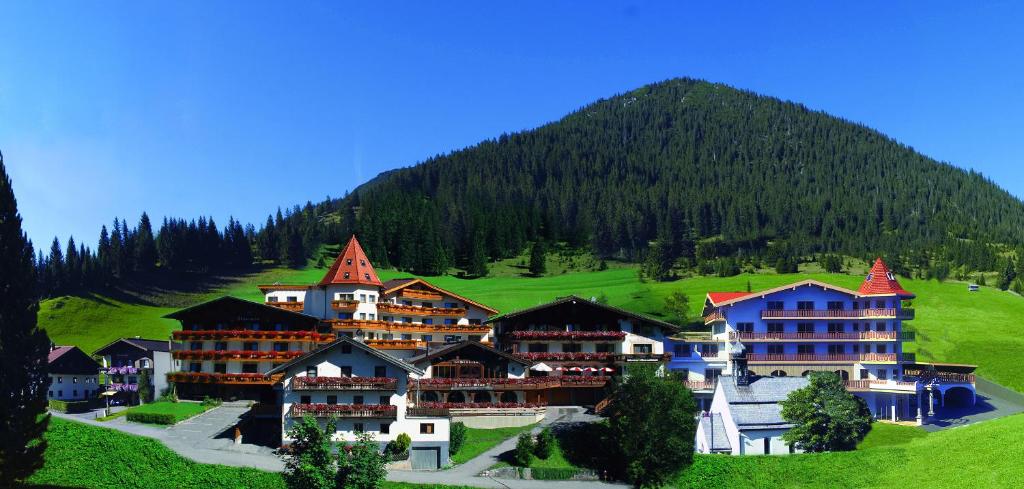 een groot gebouw op een heuvel met een berg op de achtergrond bij Hotel Thaneller Stadl Bräu in Berwang