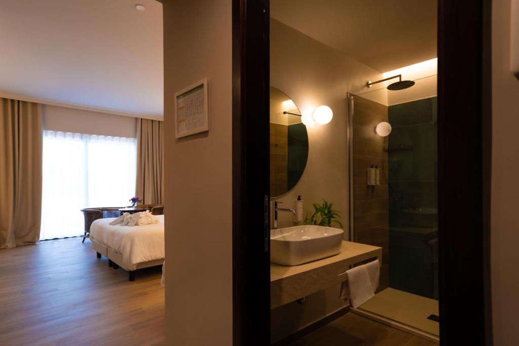 łazienka z umywalką i sypialnia z łóżkiem w obiekcie Hotel Schuhmann w mieście Paestum