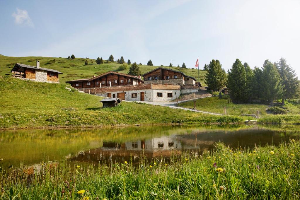 um grupo de casas numa colina ao lado de um lago em Berghuus Radons em Savognin