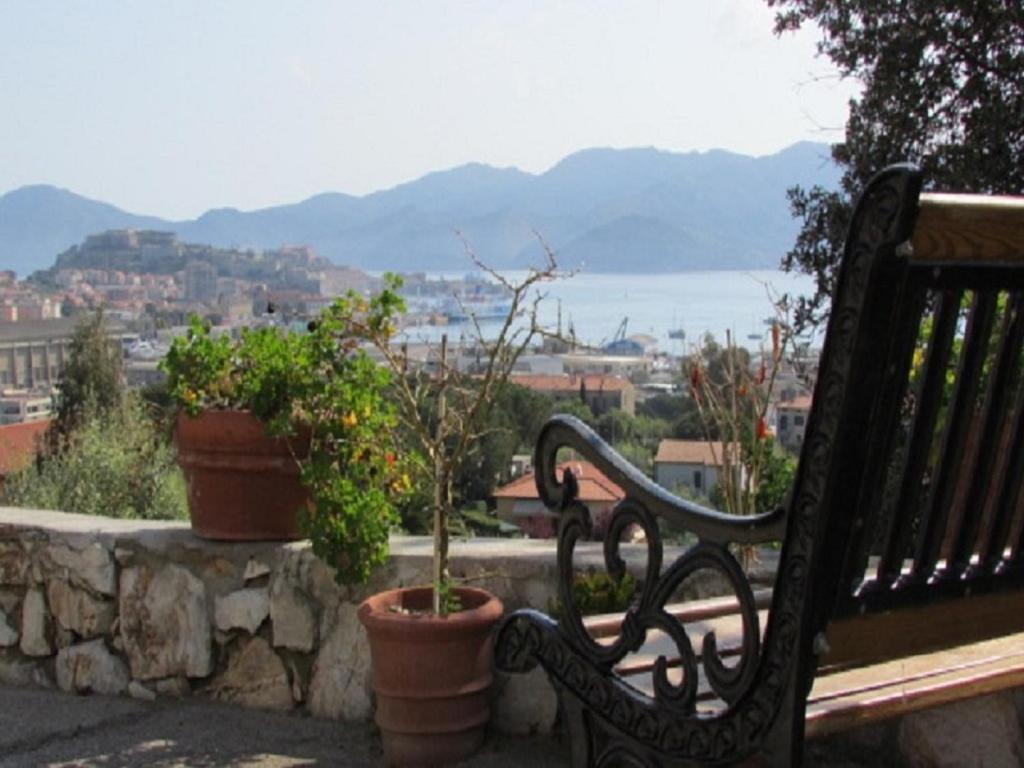 a bench sitting on a stone wall with potted plants at Appartamenti Bellavista by HelloElba in Portoferraio