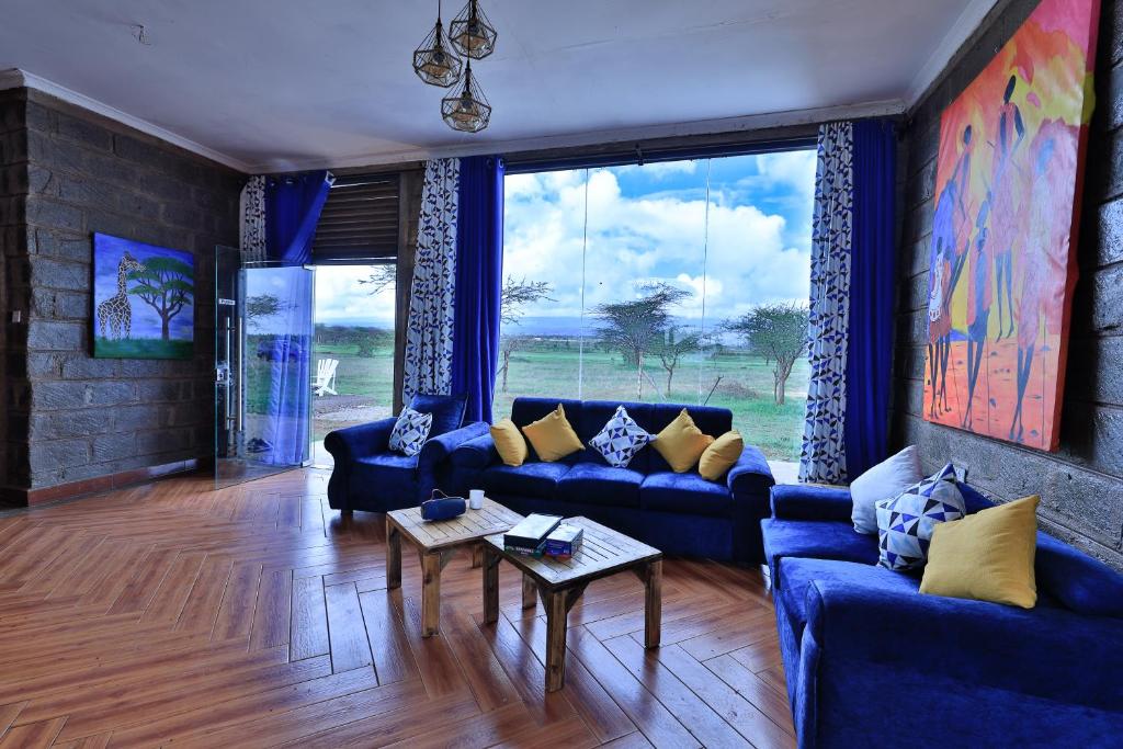 sala de estar con sofás azules y ventana grande en Amboseli Cultural Camping en Amboseli