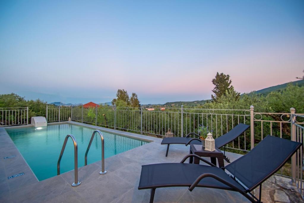 Villa Vrisi في Fayiás: مسبح مع كراسي وطاولة على شرفة
