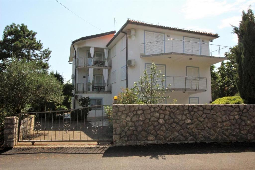 una gran casa blanca con una valla de piedra delante de ella en Apartmani Zec en Šilo