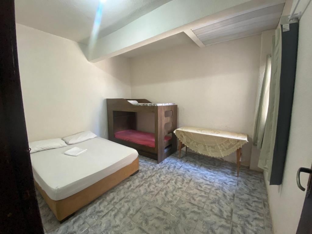 ein kleines Schlafzimmer mit einem Bett und einem Tisch in der Unterkunft Apartamento Inteiro Central 2 Quartos e Kitnet Inteira 01 quarto in Ponta Grossa