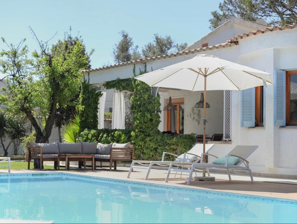 a pool with chairs and an umbrella next to a house at Villa Can Llompart Port de Pollensa in El Port