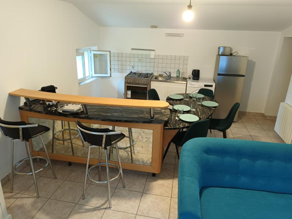 eine Küche mit einem Tisch und Stühlen sowie einem blauen Sofa in der Unterkunft gite de la basse pierre près d'Ancenis Loire in Ancenis