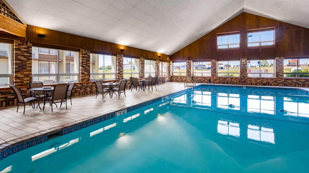 a swimming pool with chairs and tables in a building at Best Western Tomah Hotel in Tomah