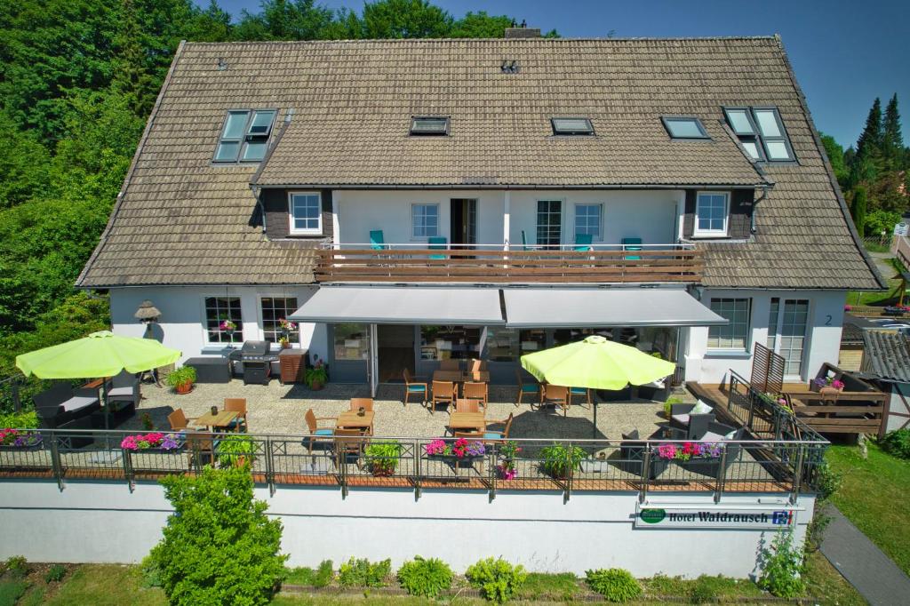 a house with a deck with chairs and umbrellas at Hotel Waldrausch in Hahnenklee-Bockswiese