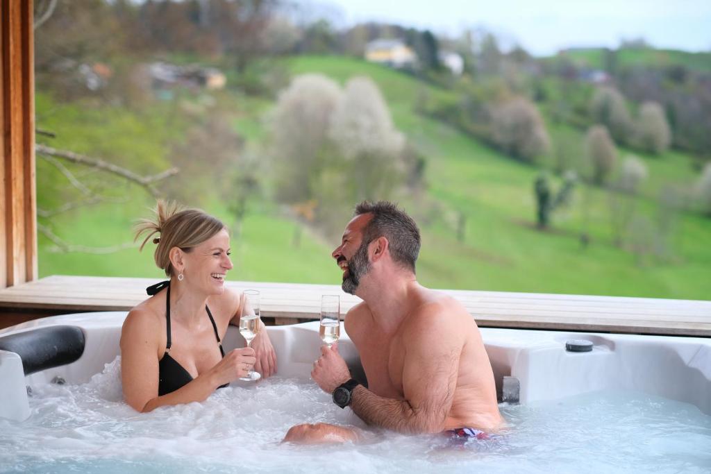 a man and woman sitting in a bath tub with champagne at Wohlfuehloase am Trausdorfberg mit Sauna/Whirlpool in Sankt Marein bei Graz