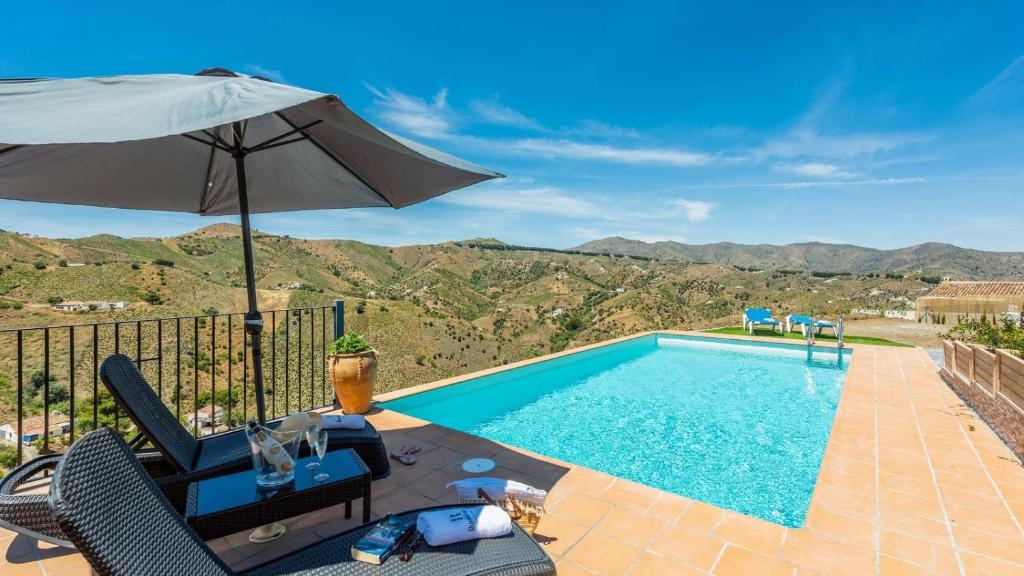 uma piscina com um guarda-sol, uma mesa e cadeiras em Casa Tortela Almáchar by Ruralidays em Almáchar