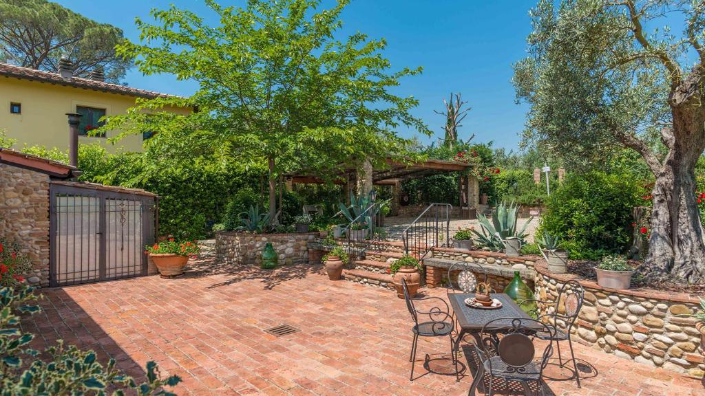 un patio avec une table et des chaises et un mur en pierre dans l'établissement VILLA GINO 8&2, Emma Villas, à Empoli