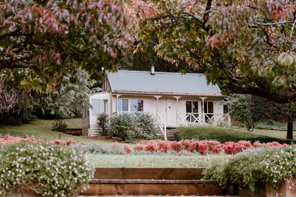 a small white house in a garden with flowers at The Mountain View Cottage in The Patch